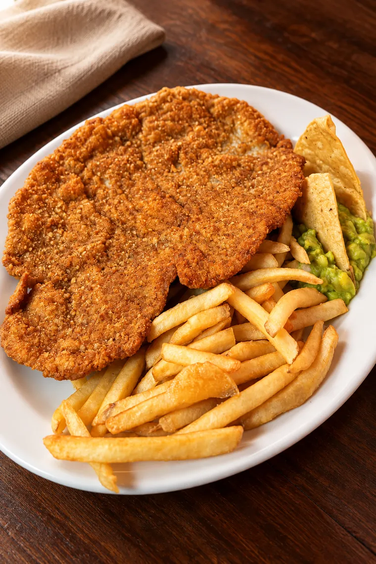 Milanesa de ternera empanizada con papas y guacamole